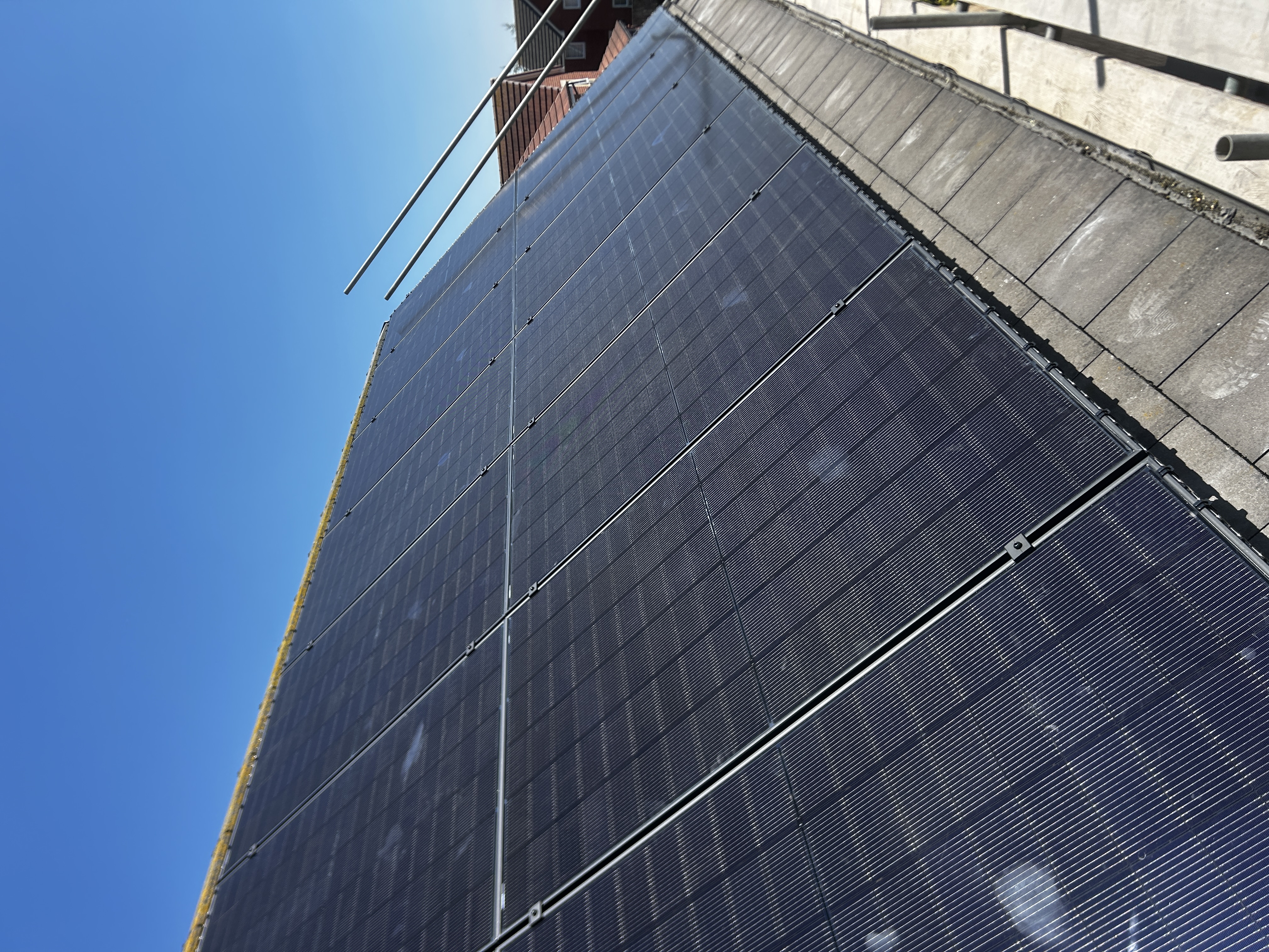 Long row of monocrystalline solar panels on a Yorkshire roof under clear blue sky